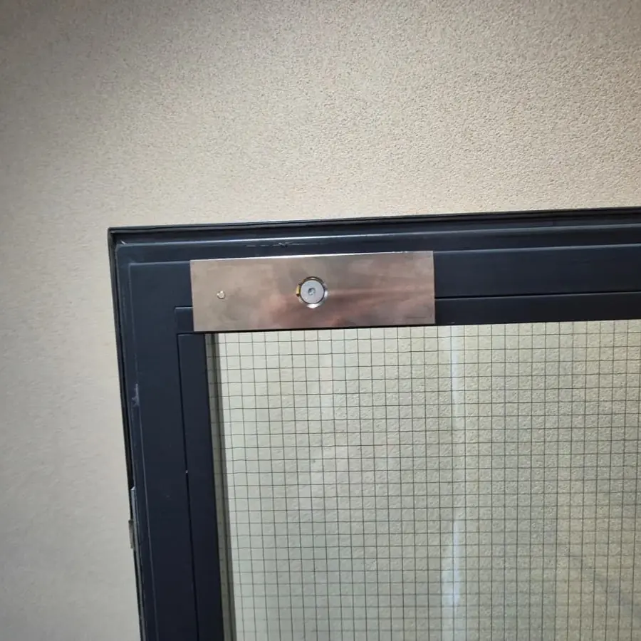 INstallation d'une ventouse magnétique réalisée par votre serrurier Neuchâtel sur un contrôle d'accès avec bouton poussoir.